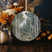 a ceramic ornament with a painting of a forest scene