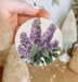 a person holding a purple flower ornament in their hand