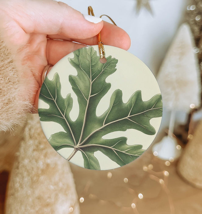 a person holding a green leaf ornament in their hand