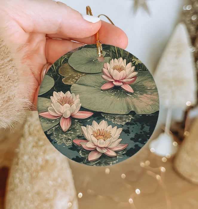 a person holding a round ornament with water lilies on it
