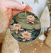 a person holding a round ornament with water lilies on it