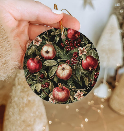a hand holding a christmas ornament with apples on it