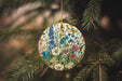 a ceramic ornament hanging from a pine tree