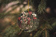 a christmas ornament hanging from a pine tree