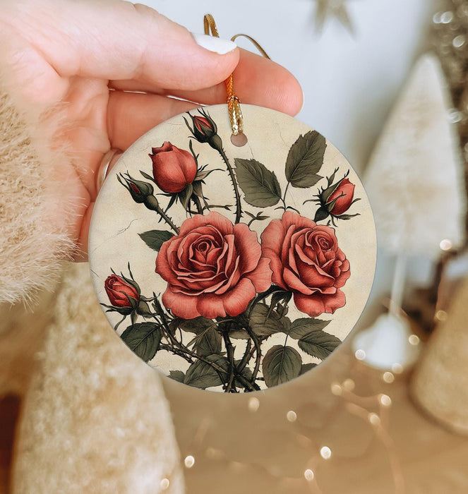 a hand holding a christmas ornament with roses on it