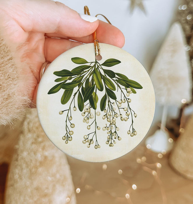 a hand holding a ceramic ornament with a green plant on it