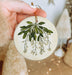 a hand holding a ceramic ornament with a green plant on it
