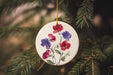 a ceramic ornament with flowers hanging from a tree