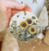 a person holding a sunflower ornament in their hand