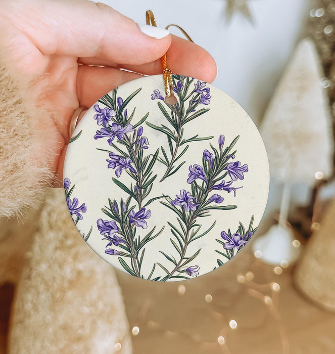 a hand holding a ceramic ornament with purple flowers