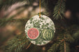 a watermelon ornament hanging from a pine tree