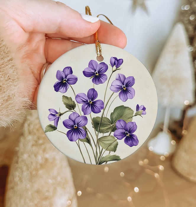 a person holding a purple flower ornament in their hand