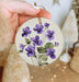 a person holding a purple flower ornament in their hand