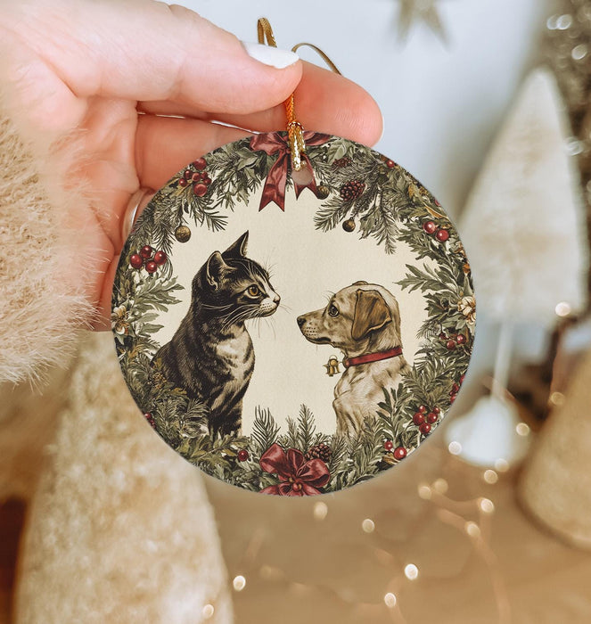a person holding a christmas ornament with a cat and dog on it