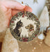 a person holding a christmas ornament with a cat and dog on it