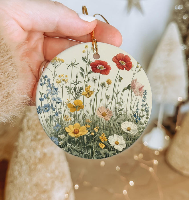 a person holding a christmas ornament with flowers on it