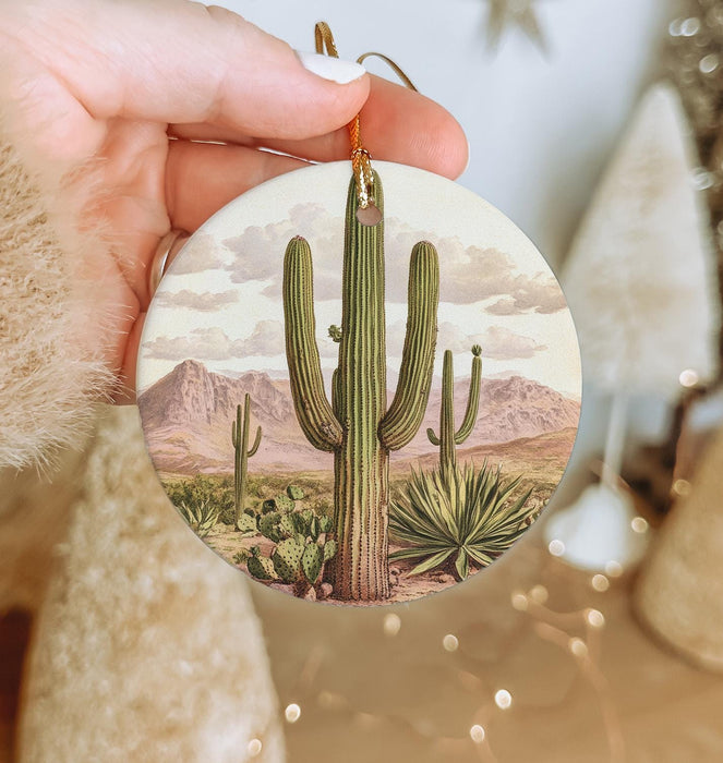 a person holding a christmas ornament with a cactus on it