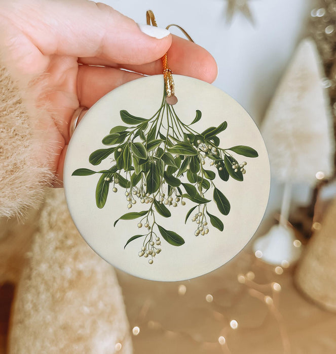 a hand holding a ceramic ornament with a plant on it