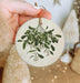 a hand holding a ceramic ornament with a plant on it