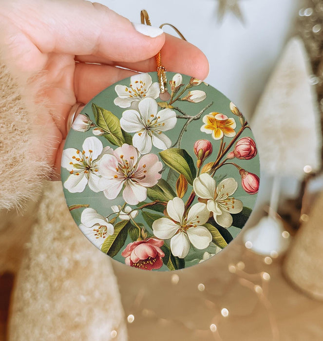 a person holding a christmas ornament with flowers on it
