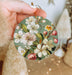 a person holding a christmas ornament with flowers on it