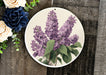 a plate with purple flowers on it next to a bouquet of flowers