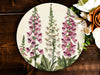a plate with flowers painted on it next to a bouquet of flowers