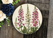 a plate with flowers painted on it next to a bouquet of flowers