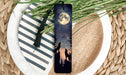 a bookmark with a picture of a wolf and a full moon