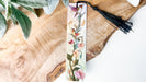 a bookmark with a tassel on top of a piece of wood