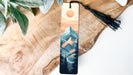 a wooden bookmark with a mountain scene on it