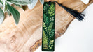 a green bookmark with leaves and berries on it