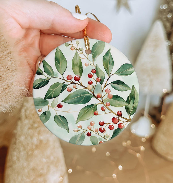 a hand holding a ceramic ornament with berries on it