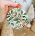 a hand holding a ceramic ornament with berries on it