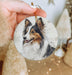 a hand holding a small ornament with a picture of a dog on it