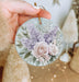 a person holding a round ornament with flowers on it