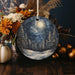 a ceramic ornament with a night sky and trees on it
