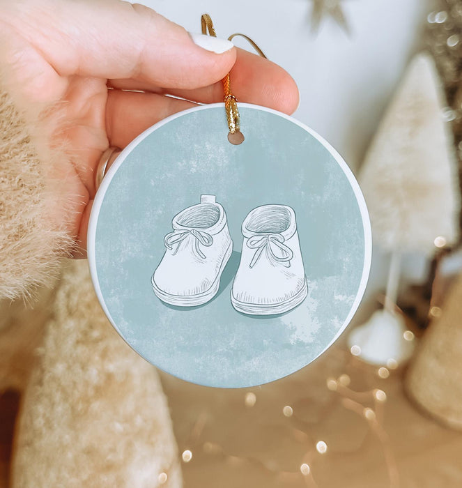 a hand holding a christmas ornament with a pair of shoes on it