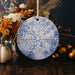 a blue and white snowflake ornament sitting on a table next to