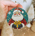a hand holding a christmas ornament with a santa clause on it