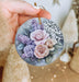 a person holding a round ornament with flowers on it