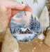 a person holding a christmas ornament in their hand