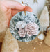 a person holding a flower ornament in their hand