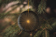 a black ornament hanging from a pine tree