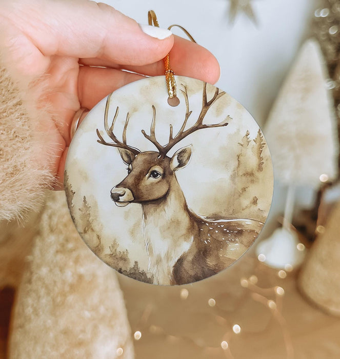 a hand holding a christmas ornament with a deer on it