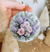 a person holding a round ornament with flowers on it