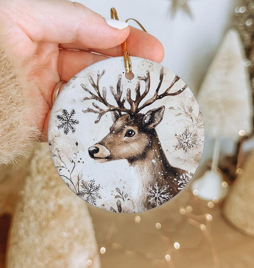 a hand holding a christmas ornament with a deer on it