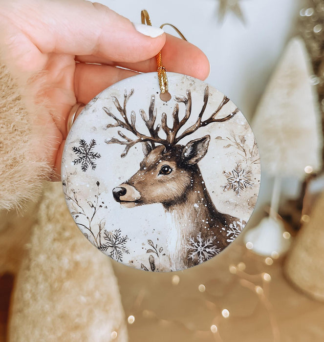 a hand holding a christmas ornament with a deer on it