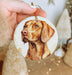 a hand holding a christmas ornament with a picture of a dog