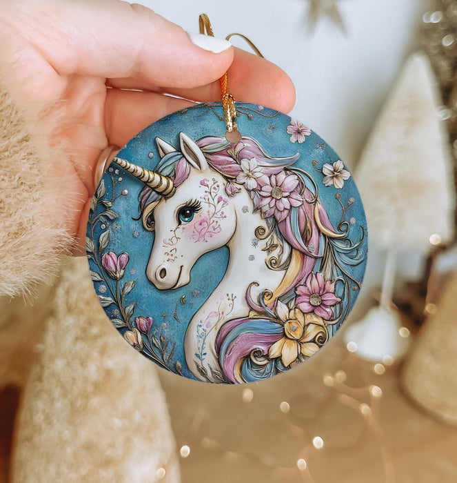 a hand holding a blue ornament with a unicorn on it